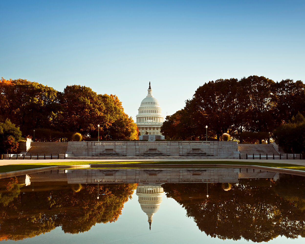 capitol building bordered with trees behind a large pond